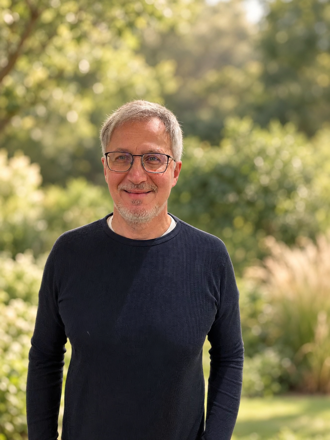 Ivo Ryssel lächelt vor einem warmen, unscharfen Naturhintergrund.